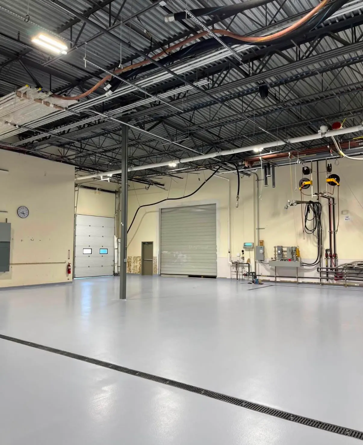 Light gray coated bay floor with a trench drain and an overhead door