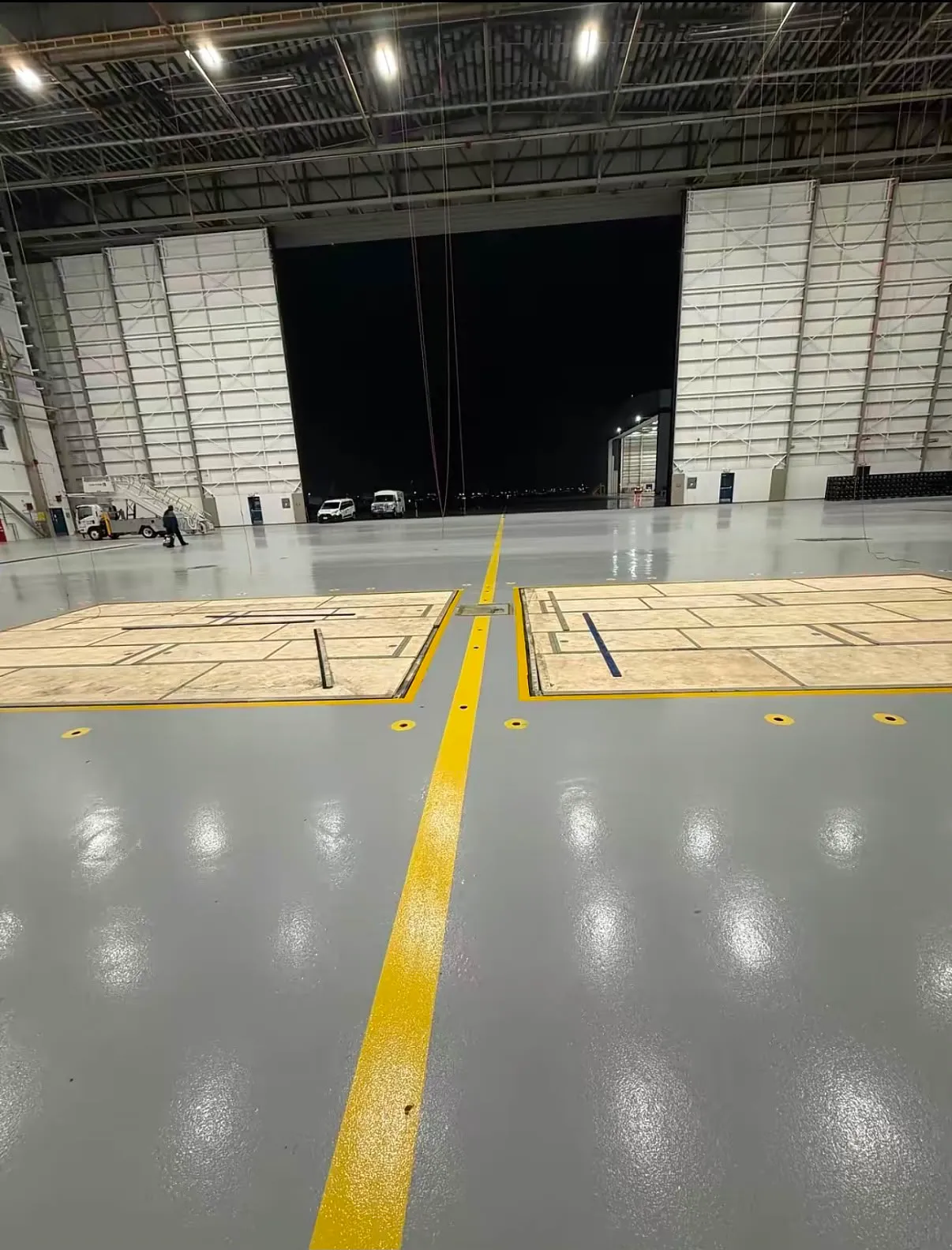 Yellow centerline on a gray hangar floor, hangar doors open at night