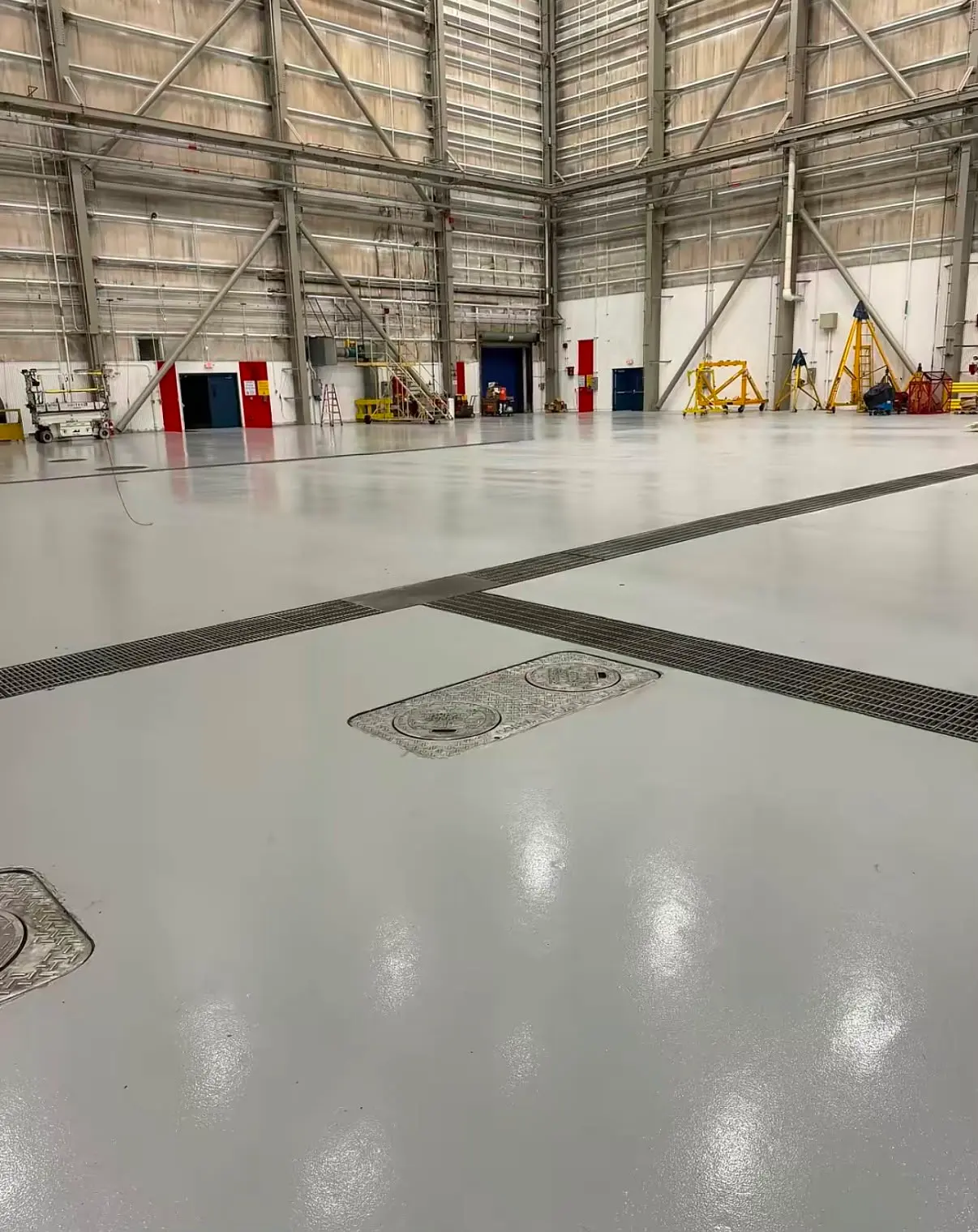 Floor access covers between trench drains in a gray hangar floor