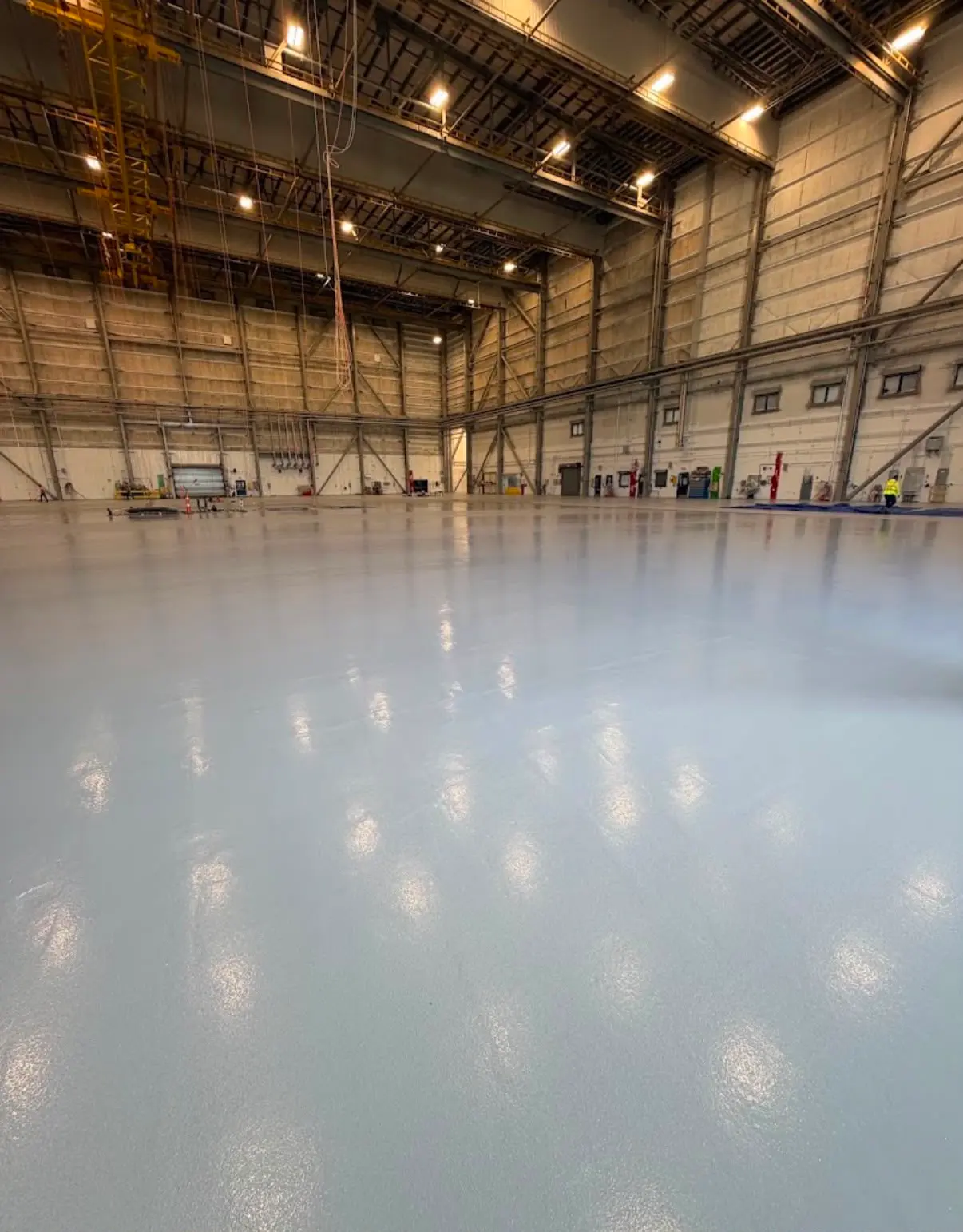 Wide glossy gray hangar floor under high work lights